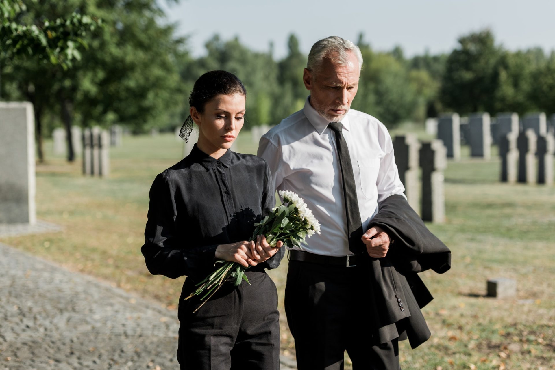 bearded-senior-man-walking-near-woman-with-flowers-on-funeral-e1636904705190.jpg